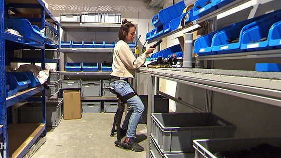 Eine Montagemitarbeiterin sitzt mit Hilfe des Exoskeletts an der Werkbank