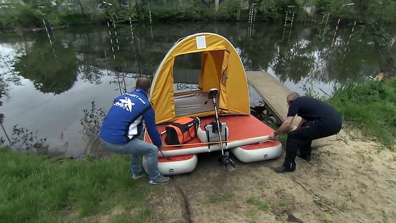 Zwei Männer lassen ein Hausboot zu Wasser