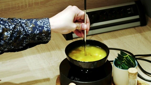 Ein Heizstab wird in eine Suppenschüssel gehalten.