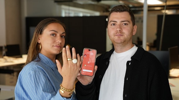 Eine Frau und ein Mann vor der kamera und halten einen Notruf-Ring und Handy in der Hand.