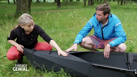Zwei Menschen bauen ein Faltboot auf.