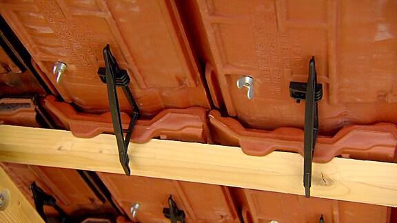 Dachziegel sind mit Clips an Dachlatten befestigt.