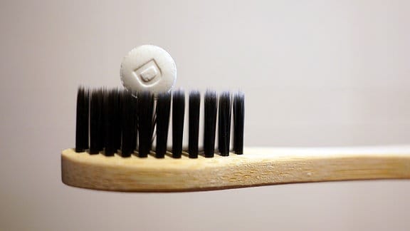 Illustration Zahntablette - Eine Pille auf den Borsten einer Zahnbürste