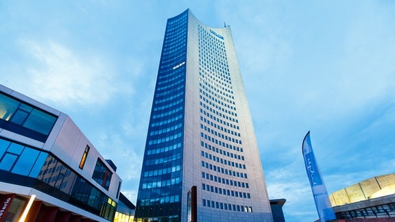 Wolkenkratzer aus Froschperspektive am Abend: City-Hochhaus in Leipzig mit Mensa-Gebäude und Teile von Gewandhaus daneben.