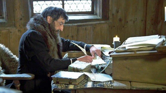 Darsteller von Martin Luther schreibt mit Feder in Schreibstube 