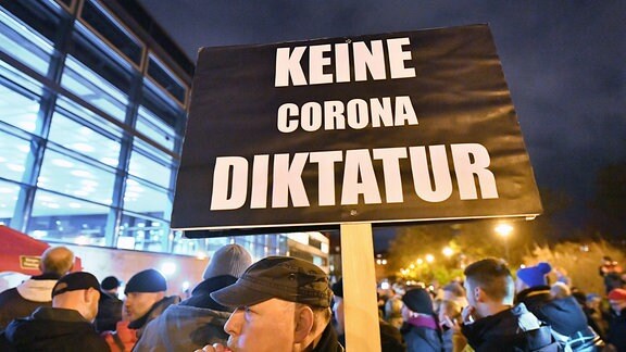 «Keine Corona Diktatur» steht auf dem Plakat, das ein Mann bei einer Demonstration vor dem Thüringer Landtag in den Händen hält