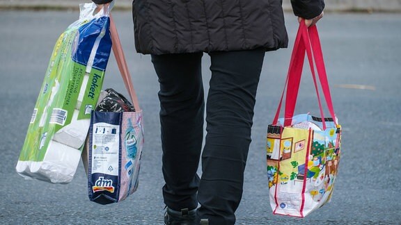 Person trägt mehrere Einkaufstaschen