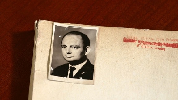 Das Schwarz-Weiß Porträt eines Mannes ist an eine Akte getackert.