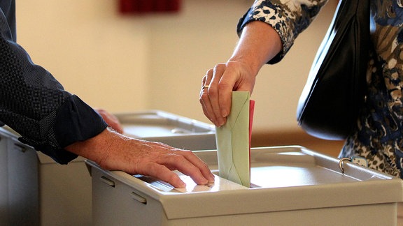 Wählerin wirft Wahlumschlag in eine Wahlurne.