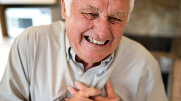 Ein älterer Mann greift sich an die Brust