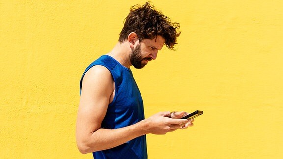 Ein junger Mann sieht auf sein Smartphone