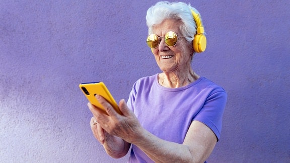 Fesche Oma mit Kopfhöhrern und Smartphone