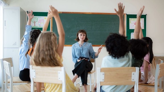 Schüler und eine Lehrerin sitzen im Kreis