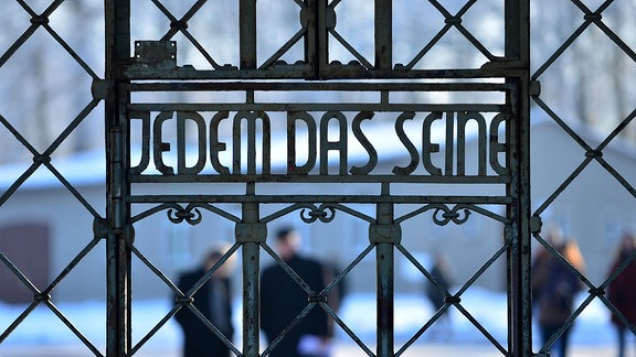 Besucher stehen am Lagertor der KZ-Gedenkstätte Buchenwald bei Weimar mit der Inschrift Jedem das Seine