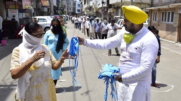 Ein Mann verteilt in Katra Sher Singh Gesichtsmasken an die Menschen