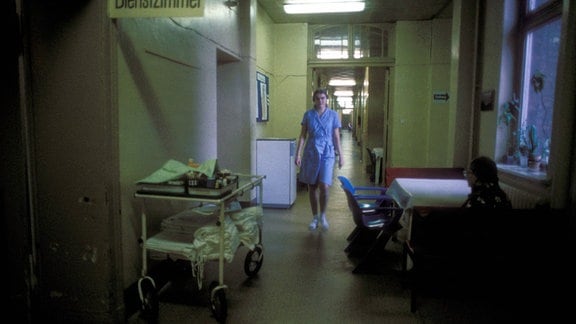 Eine Frau läuft durch einen dunklen Flur eines Krankenhauses.