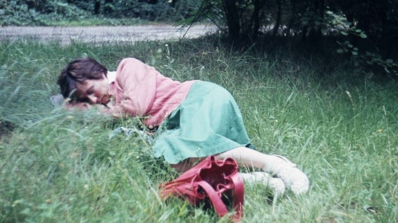Frau schläft im Gras.