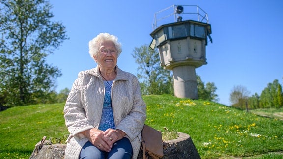 Die Zeitzeuging Gitta Kappe sitzt am «Grenzdenkmal Hötensleben» vor einem ehemaligen Wachturm