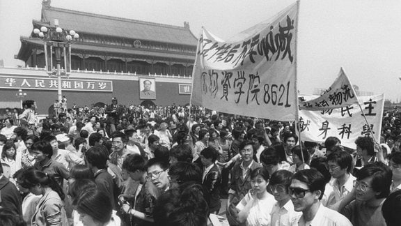Historische Schwarzweiß-Aufnahme: Demonstrierende mit Transparenten auf einem chinesischen Platz.