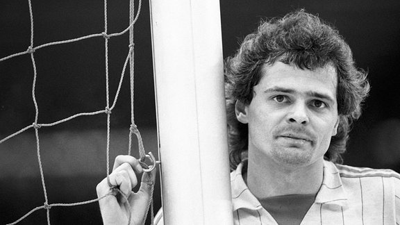Sportler Lutz Eigendorf lehnt am Tor und hält sich am Netz fest, 1983