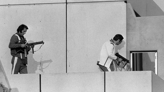 Polizisten in Trainingsanzügen stürmen das Gebäude in der Conollystraße 31 im Olympischen Dorf mit Schnellfeuerwaffen, 1972.