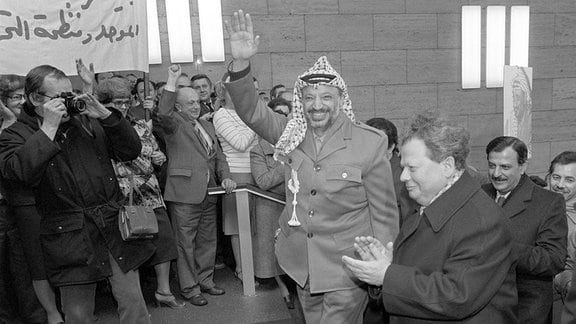 Der Chef der Palästinensischen Befreiungsbewegung PLO, Yasser Arafat (M, winkend) wird am 09.03.1982 in Berlin (Ost) im Foyer des Gebäudes der Zentralkomitees der SED von Mitarbeitern des Hauses begrüßt. 