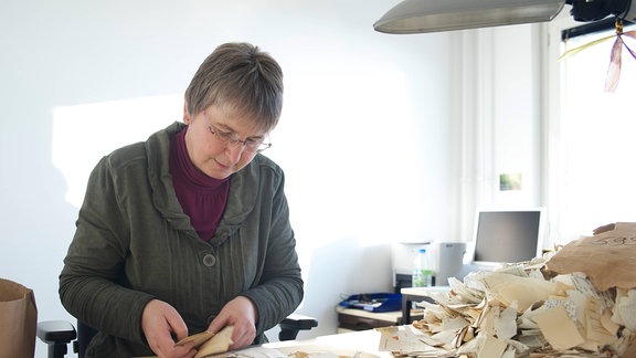 Eine Frau sortiert zerstörte Stasi-Akten