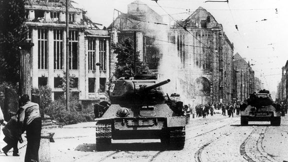  Berliner bewerfen einen sowjetischen Panzer in der Leipziger Straße nahes des Potsdamer Platzes in Berlin mit Steinen.