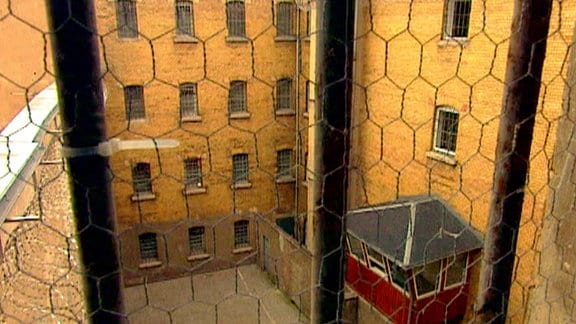 Blick durch vergittertes Fenster in Gefängnishof