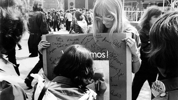 Eine Frau setzt ihre Unterschrift ein Plakat, welches Solidarität für Salvador Allende fordert. 