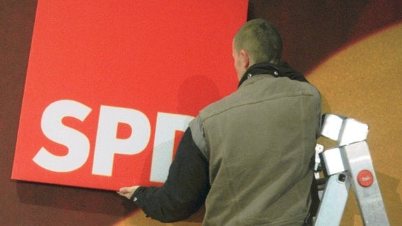 Ein Mann auf einer Leiter hängt ein SPD-Logo ab.