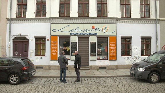 Zwei Männer stehen vor einem Laden.