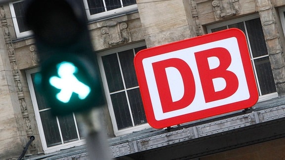 Logo der Deutsche n Bahn DB hinter einer grünen Fußgängerampel am Hauptbahnhof Leipzig