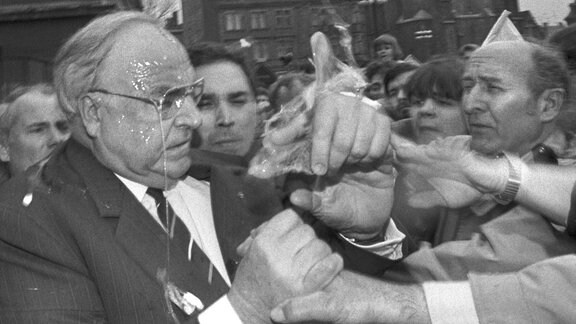 Das Eiweiß tropft Bundeskanzler Helmut Kohl in Halle von der Brille, während er versucht, den Eierwerfer in der ihm ansonsten zujubelnden Menge ausfindig zu machen, 1991