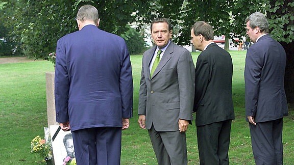 Der deutsche Bundeskanzler Gerhard Schröder, zweiter von rechts, und Mitglieder seiner Delegation erinnern an der Gedenkstele für den Mosambikaner Alberto Adriano in einem Park in der Stadt Dessau am Donnerstag, den 31. August 2000.