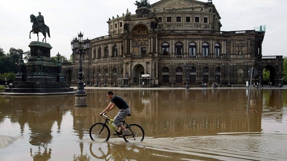 Radfahrer fährt unbedarft durch das Hochwasser vor der Semperoper in Dresden, 2002