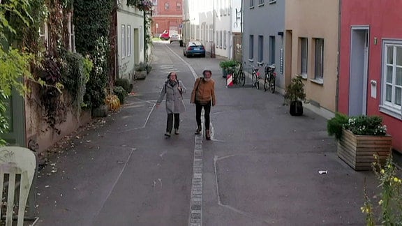 Zwei Personen gehen auf einer Straße.