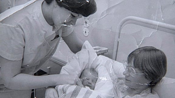 Schwarzweiß-Bild von Frau mit neugeborenem Kind in Krankenhaus.