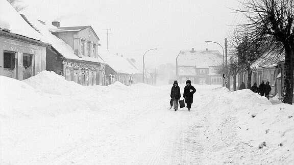 Zwei Menschen laufen durch eine schneebedeckte Straße.