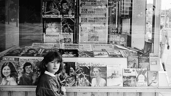 Mädchen vor einem Kiosk des Post-Zeitungs Vertriebes PZV der DDR in der Dunkerstrasse, das Sortiment besteht aus Zeitungen und Zeitschriften der DDR