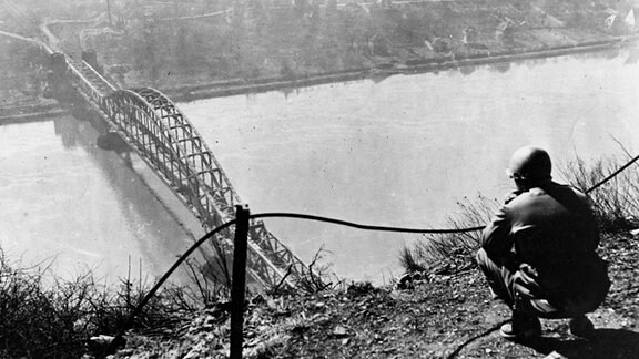 US-Soldat schaut im März 1945 auf die Ludendorff-Brücke über den Rhein bei Remagen 