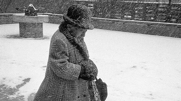 Eine ältere Frau läuft durch den Schnee.