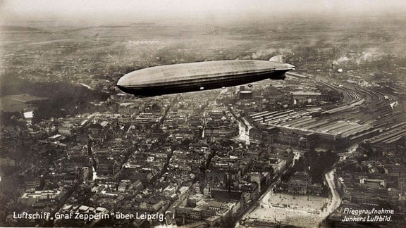 Ein Zeppelin fliegt über eine Stadt. 