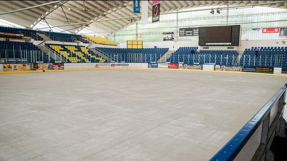 Eissporthalle Chemnitz. Im Vordergrund Eisfläche, im Hintergrund blau-gelbe Besucherränge