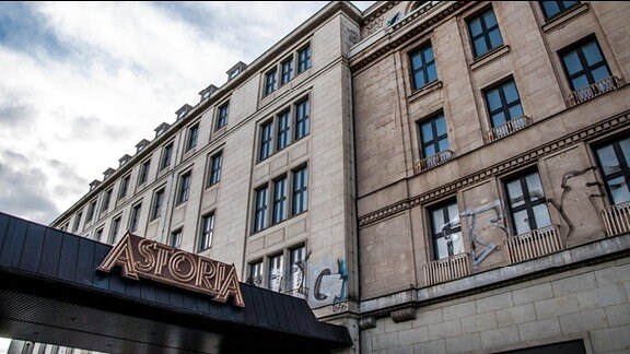 Ehemaliges Hotel „Astoria“ in Leipzig. Im Vordergrund überdachter Eingang zum Hotel mit dem Schriftzug „Astoria“. Das ungenutzte Gebäude ist mit Graffiti beschmiert.