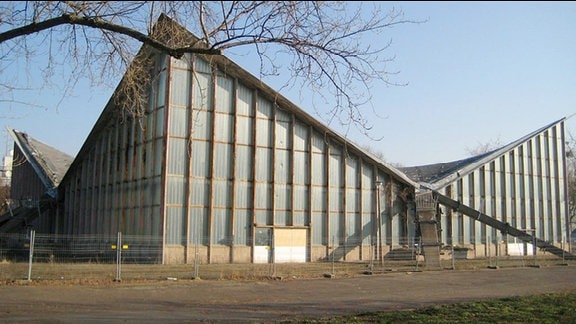 Hyparschale. Mehrzweckhalle aus dem Jahre 1969 im Magdeburger Kulturpark Rotehorn. Fassade besteht aus Glas, die vier Ecken des Gebäudes streben nach oben.