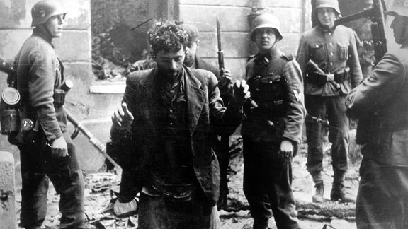 Zwei jüdische Männer, die sich in einem Haus versteckt hatten, werden 1944 von SS-Soldaten gefangen genommen.