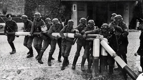 Deutsche Soldaten durchbrechen 1939 einen Schlagbaum an der Grenze zu Polen.