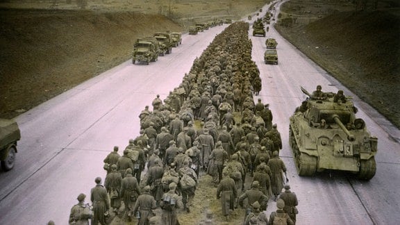 Gefangene deutsche Soldaten und US-Truppen 1945 auf einer Autobahn