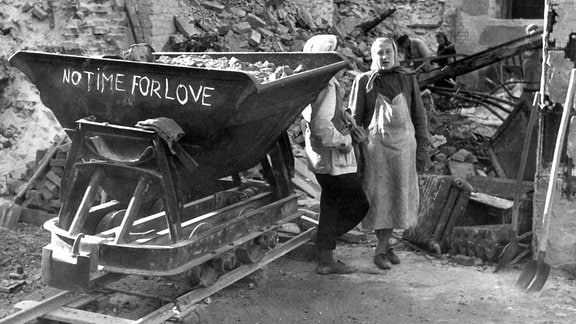 "No Time For Love" ("Keine Zeit fuer Liebe") steht 1946 auf einer Lore auf Schienen, mit der Berliner Trümmerfrauen Schutt abtransportieren.